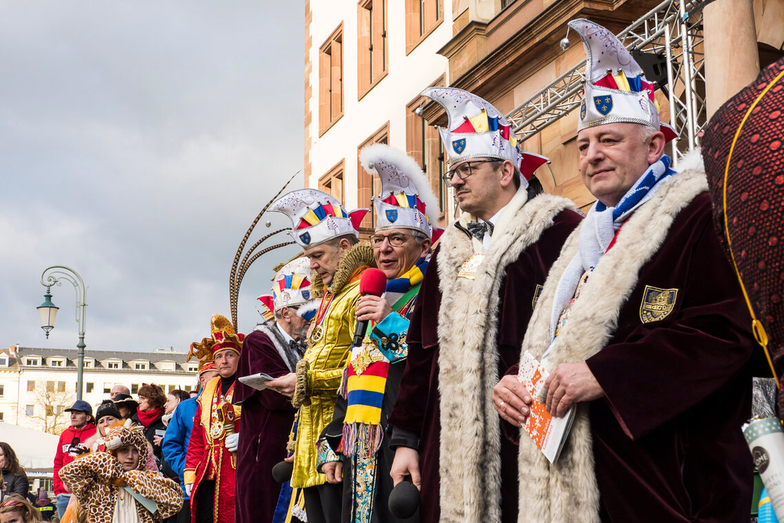 Fastnacht vor dem Rathaus. Viele Männer und Frauen in Verkleidung.