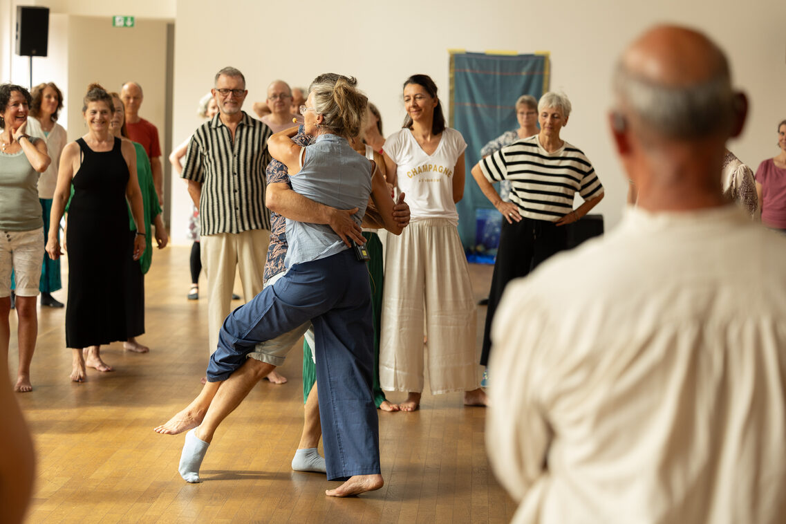 Ein Paar tanzt eng aneinander geschmiegt. Im Hintergrund weitere Personen.