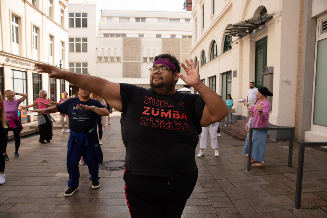 Eine Gruppe tanz Zumba auf einem Platz.