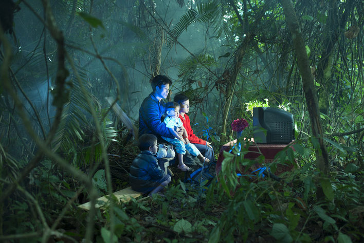 Asiatische Familie schaut Fernsehen im Urwald