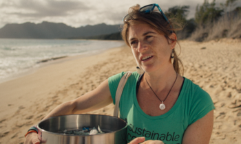 Frau mit Mülltonne am Strand