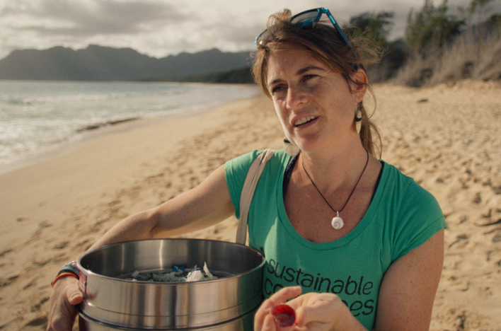 Frau mit Mülltonne am Strand