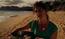 Frau am Strand sammelt Plastik