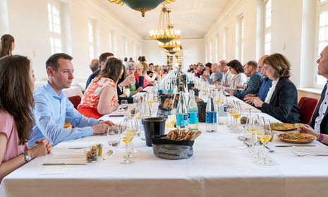 Männer und Frauen an einer langen Tafel