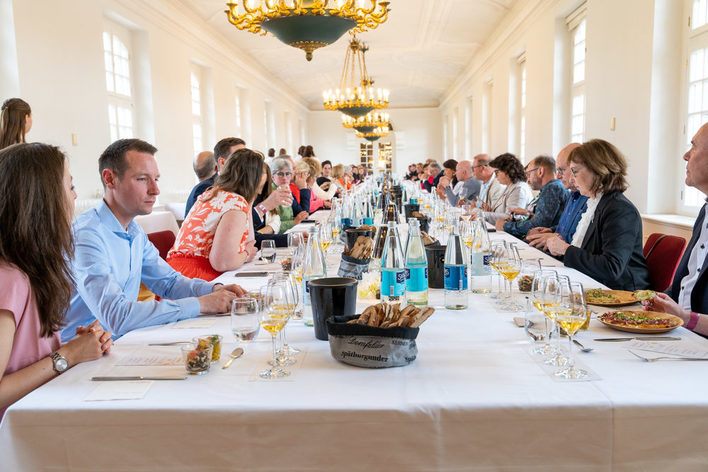 Männer und Frauen an einer langen Tafel