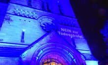 Ringkirche in blauem Licht - Schriftzug Nein zur Todesstrafe