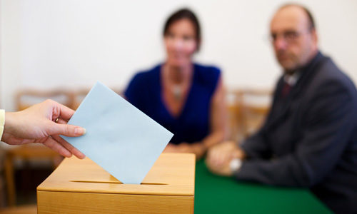 Briefwahl Bundestagswahl - Mensche wirft Umschlag in Wahlurne.