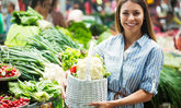 Junge Frau, die Gemüse auf dem Markt kauft