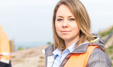 Junge Frau mit Arbeitskleidung und orangefarbener Weste