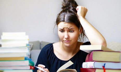 Frau sitzt genervt über Büchern.